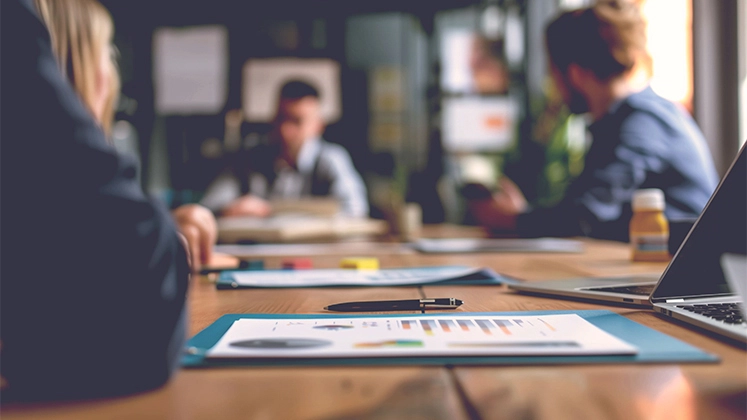 Arbeitsmeeting mit Fokus auf geschäftlichen Unterlagen und Grafiken.